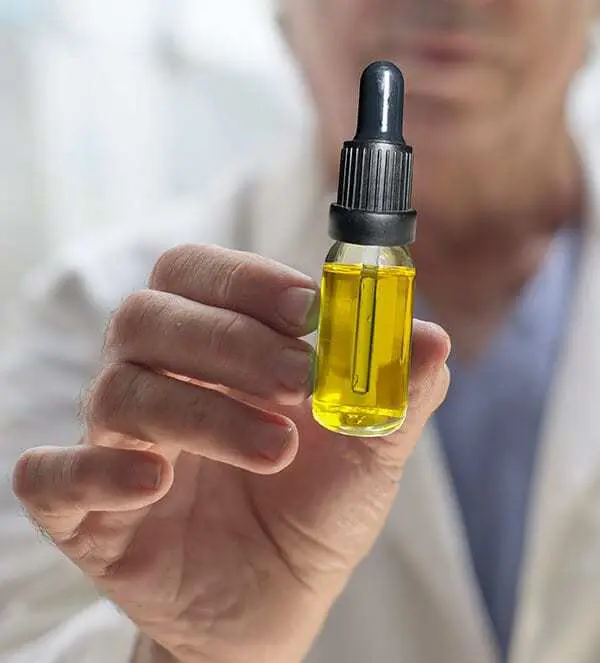 A doctor holding a dropper bottle of hemp extract oil
